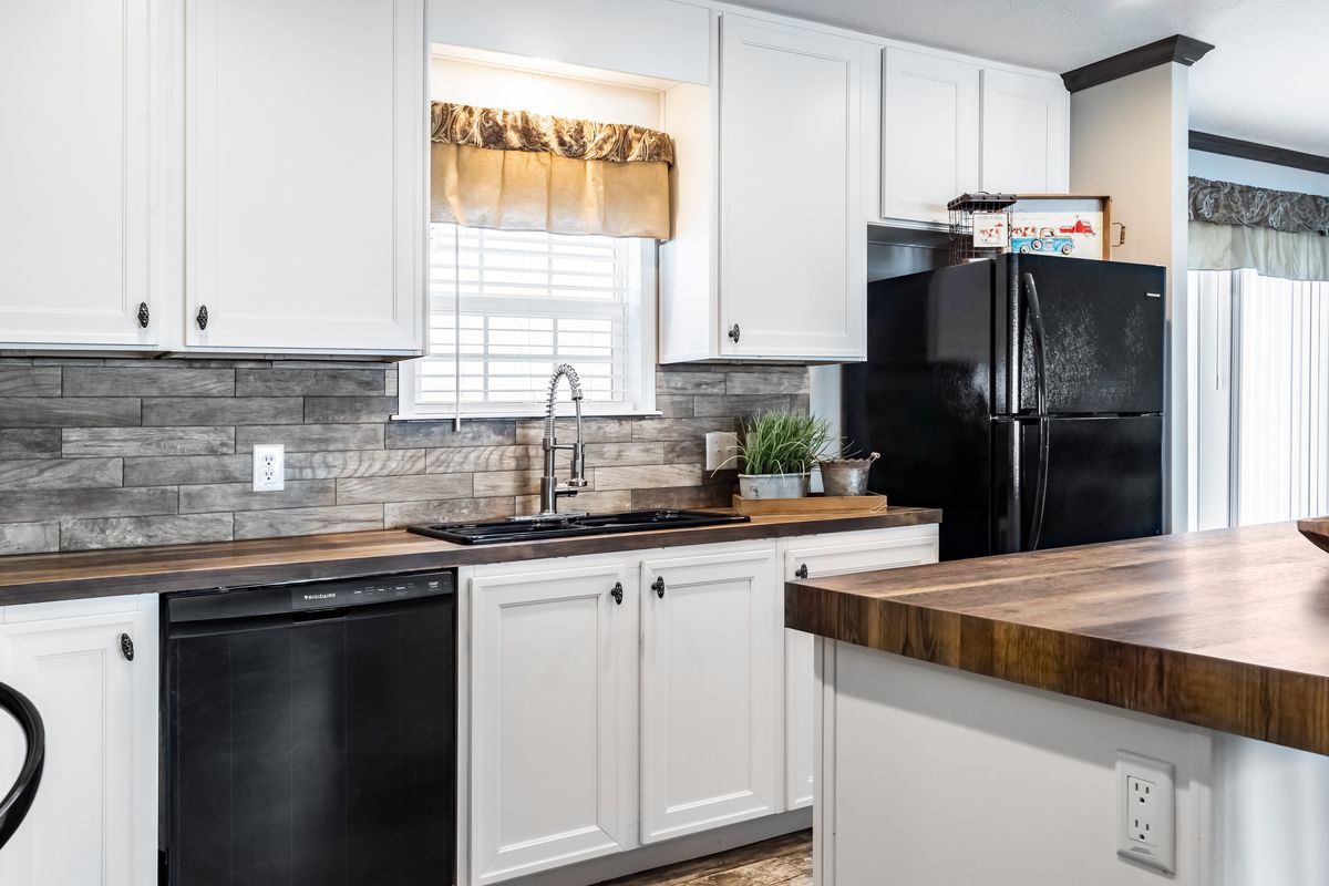 A kitchen with white cabinets and black counter tops.