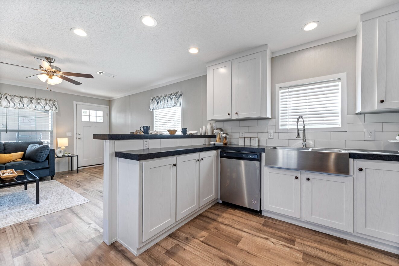 the_clarke_52769723696_o_1679953680432_1323_12 A kitchen with white cabinets and stainless steel appliances.