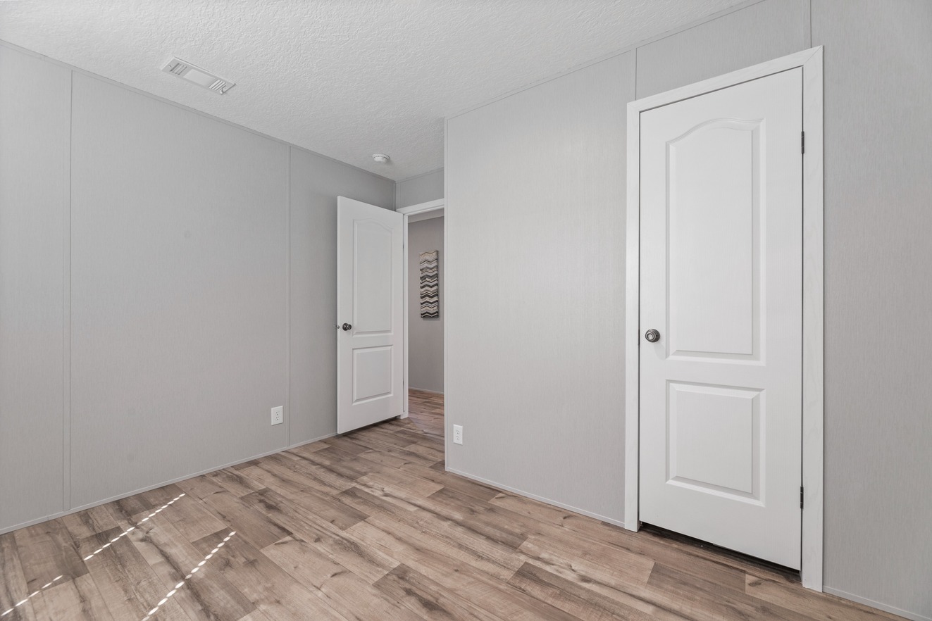 the_clarke_52769980609_o_1679953644451_1323_12 An empty room with white walls and wood floors.