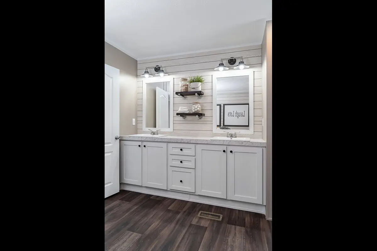A bathroom with white cabinets and a wood floor.