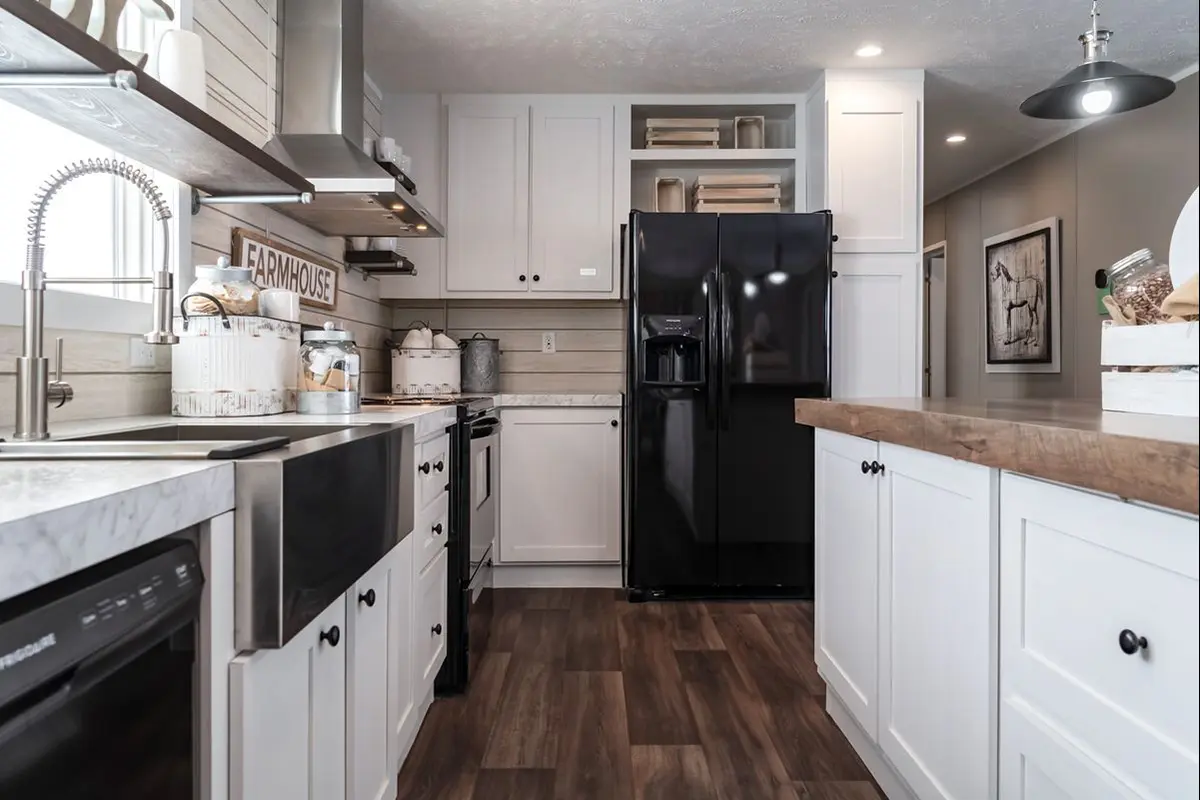 A kitchen with white cabinets and black refrigerator.