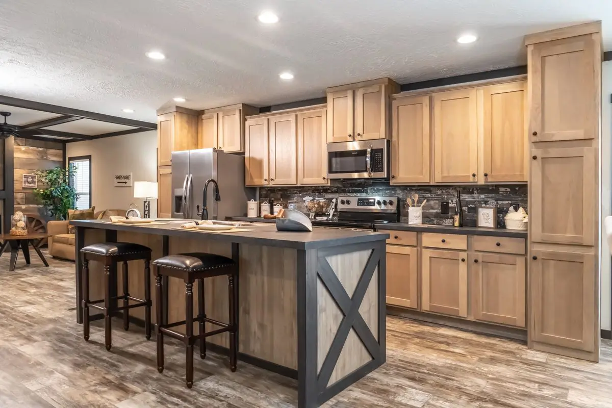 Modern kitchen interior with wooden cabinets, stainless steel appliances, a center island with stools, and a tiled backsplash.