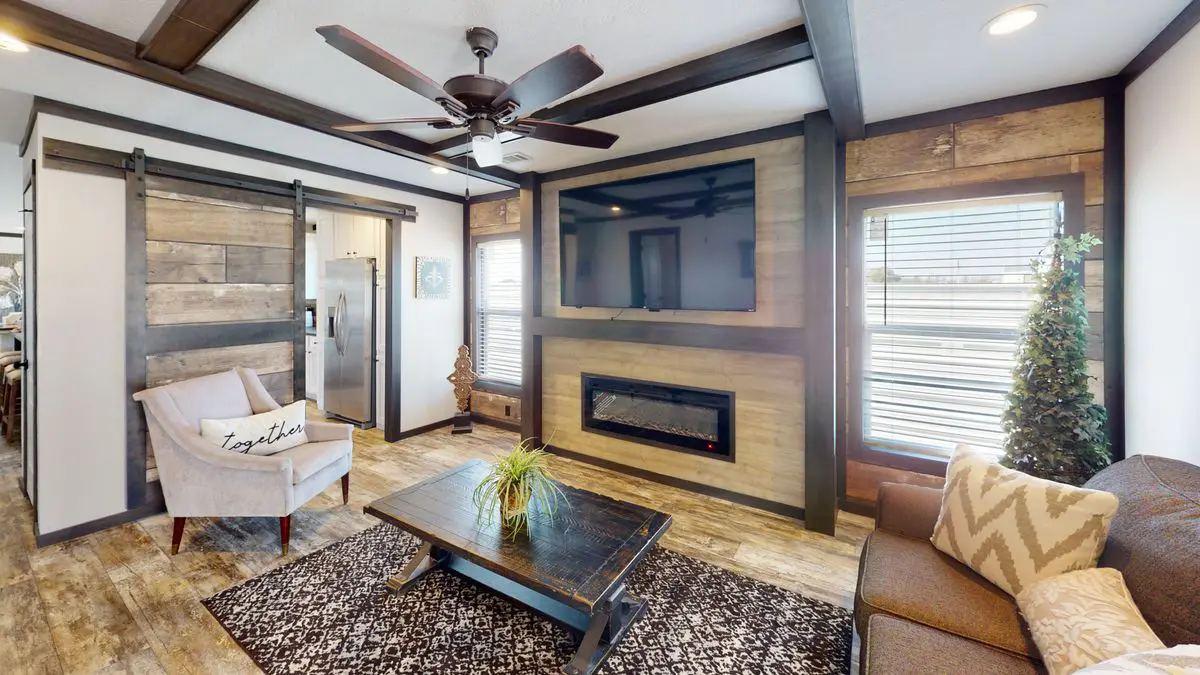 71bd5f0a-0945-4beb-9ebf-ff6867b5a2bb A cozy living room with rustic wood accents, a sliding barn door, modern furniture, and an electric fireplace under a wall-mounted tv.