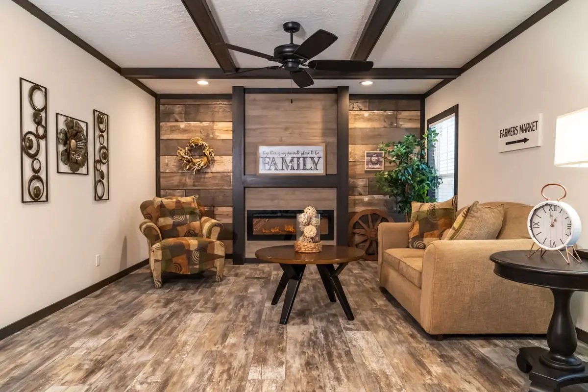 Cozy living room with two sofas, a central coffee table, and a fireplace surrounded by wooden panels. decor includes wall art and a ceiling fan.