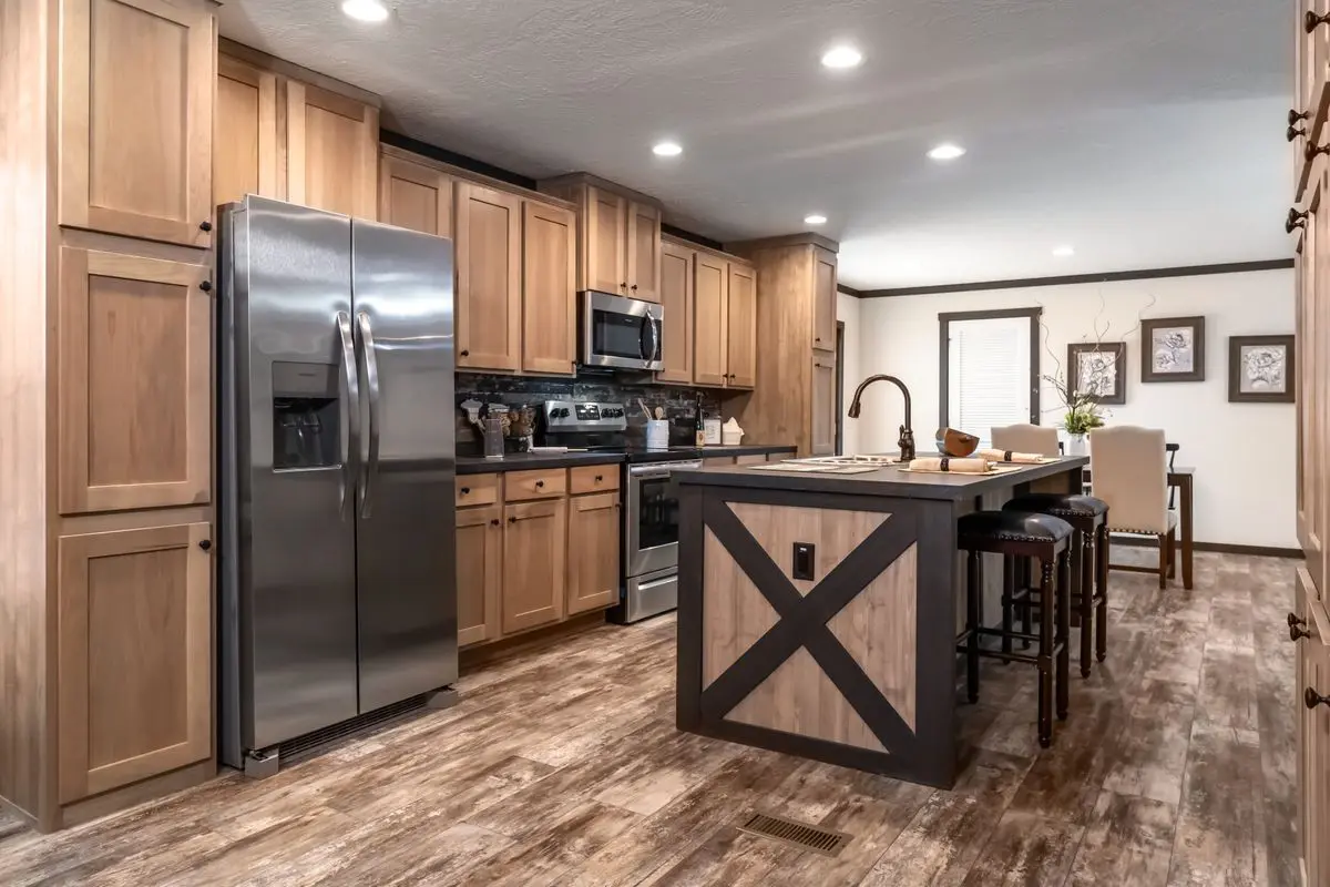 Modern kitchen with wooden cabinets, stainless steel appliances, an island with a black base, and vinyl wood flooring.