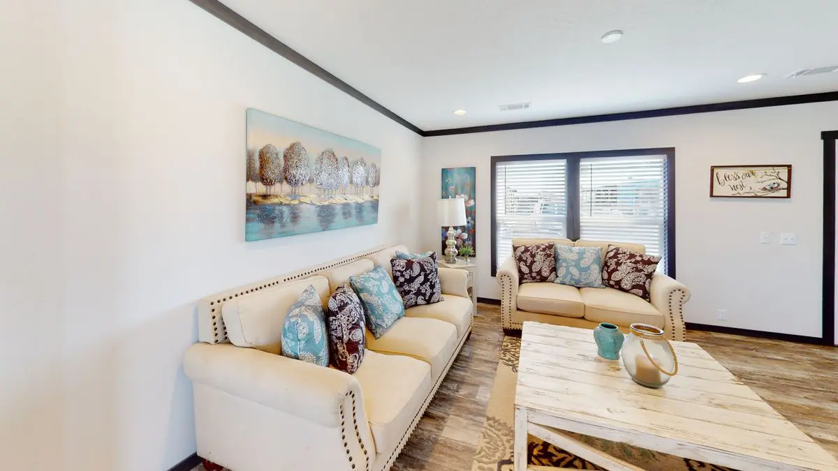 f16e68b4-5e1c-48d7-af95-7156d3b92fef Bright living room with two patterned sofas, a coffee table, decorative wall art, and windows with blinds.