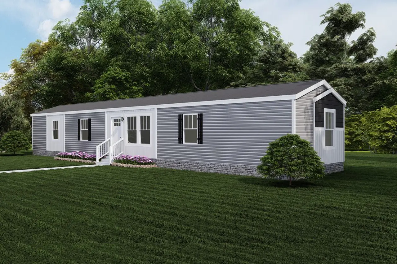 Baby-Boujee-e3e55e77-be24-460d-af14-ab3af4c9df23 A single-story, gray mobile home with white trim, front steps, and a small garden with pink flowers on a well-maintained grassy lawn, surrounded by trees.