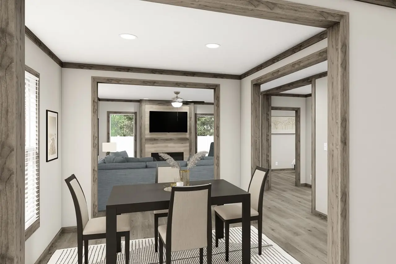 A modern open-concept dining and living area with wooden beams, a black dining table with four chairs, and a view of a living room with a TV. The space has light-colored walls and wooden flooring.
