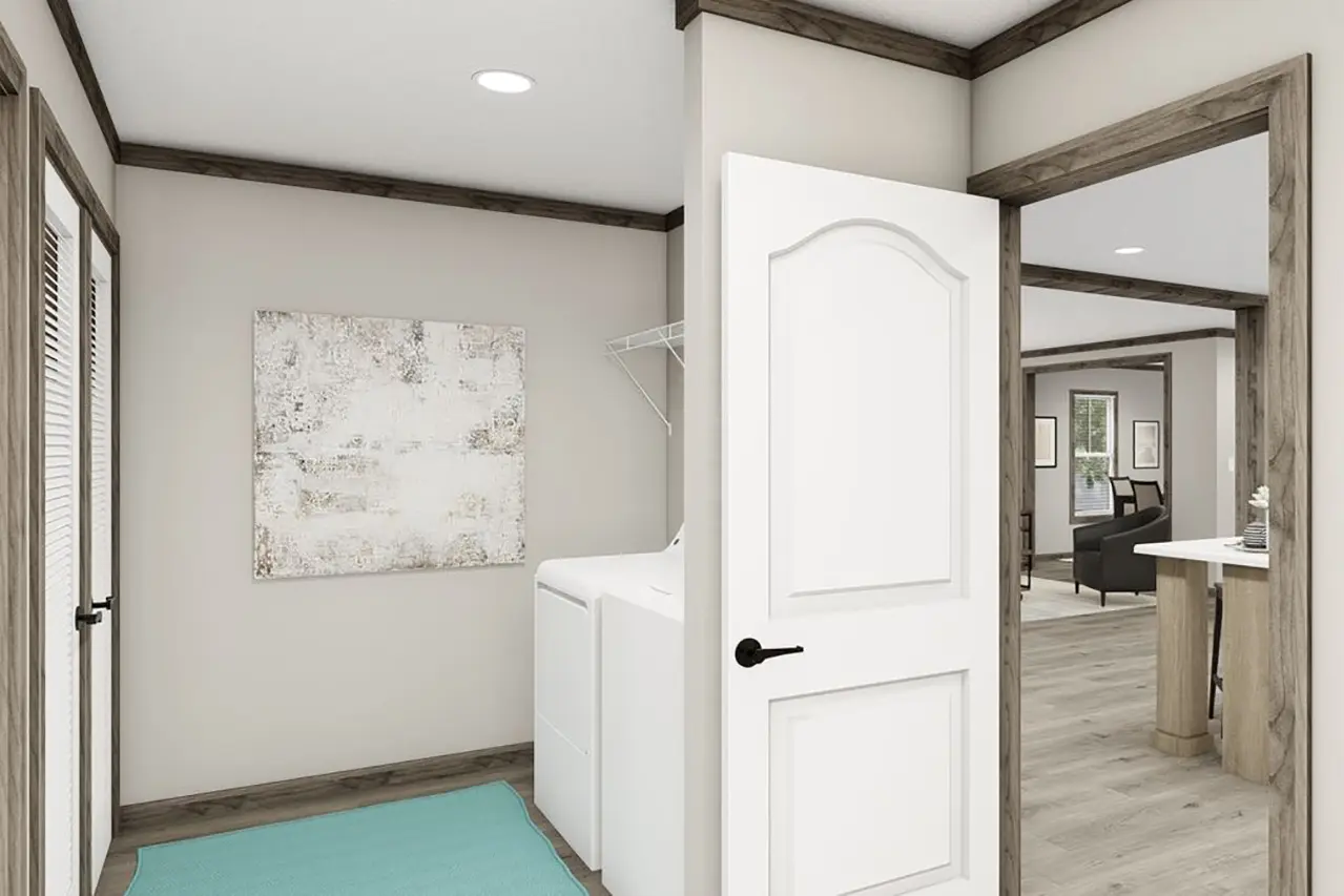 Room with an open door leading to a laundry area featuring a washer and dryer, light-colored walls, a painting on the wall, and wood-trimmed ceiling.