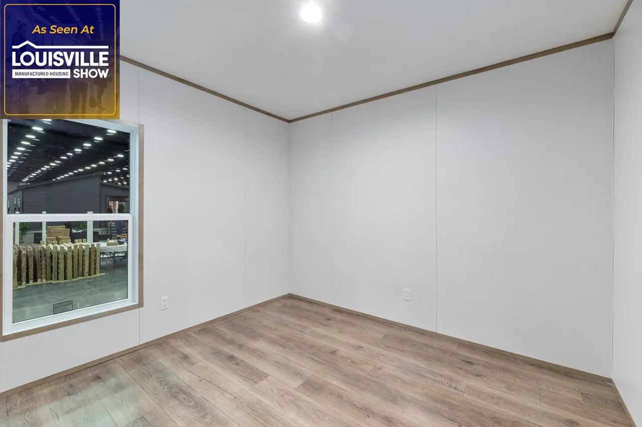 An empty room with white walls, wood flooring, and a single window. A light fixture is on the ceiling. A "Louisville Show" banner is in the top left corner.