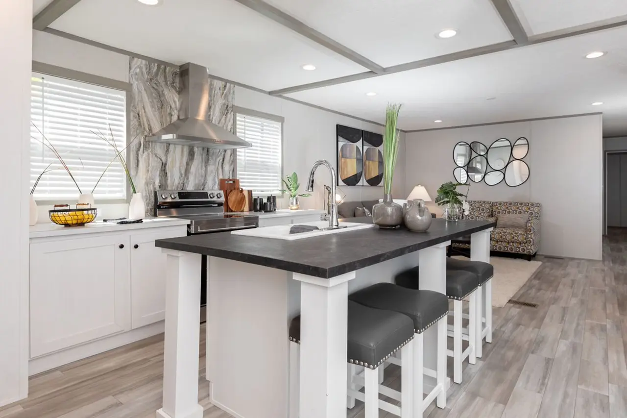 8afa9cea-932c-4f16-9491-ed448bb52a2e Modern kitchen with a center island, barstools, stainless steel appliances, and decorative art on white walls. Light wood flooring complements the sleek design.