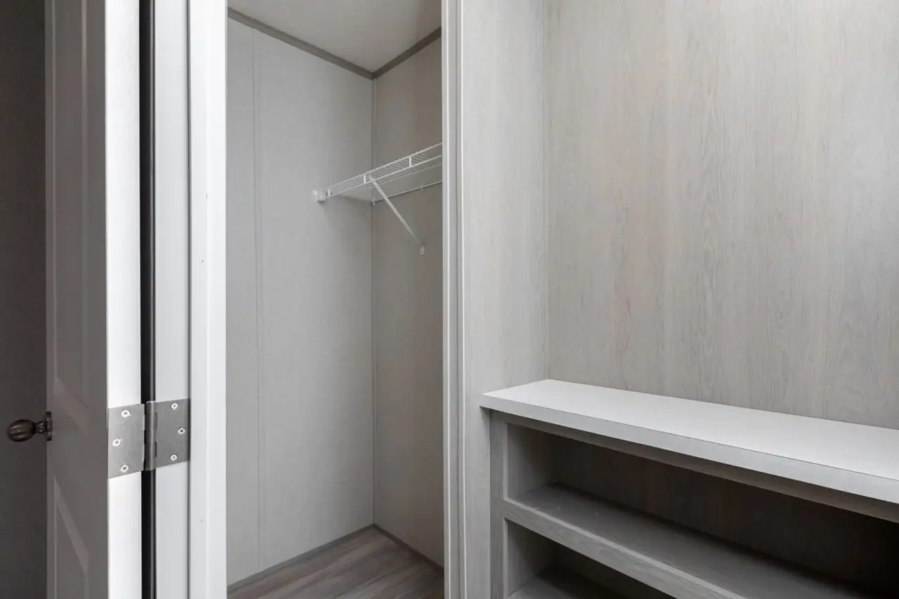 97b4800a-bbad-4fca-bd8e-5ea737c0999a Empty closet with white walls, a wire shelf, and open shelving on the right side.