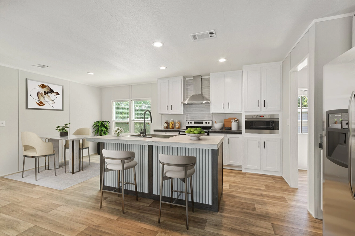 Modern kitchen with white cabinets, stainless steel appliances, a large island with two bar stools, and a small dining area with a table and two chairs.