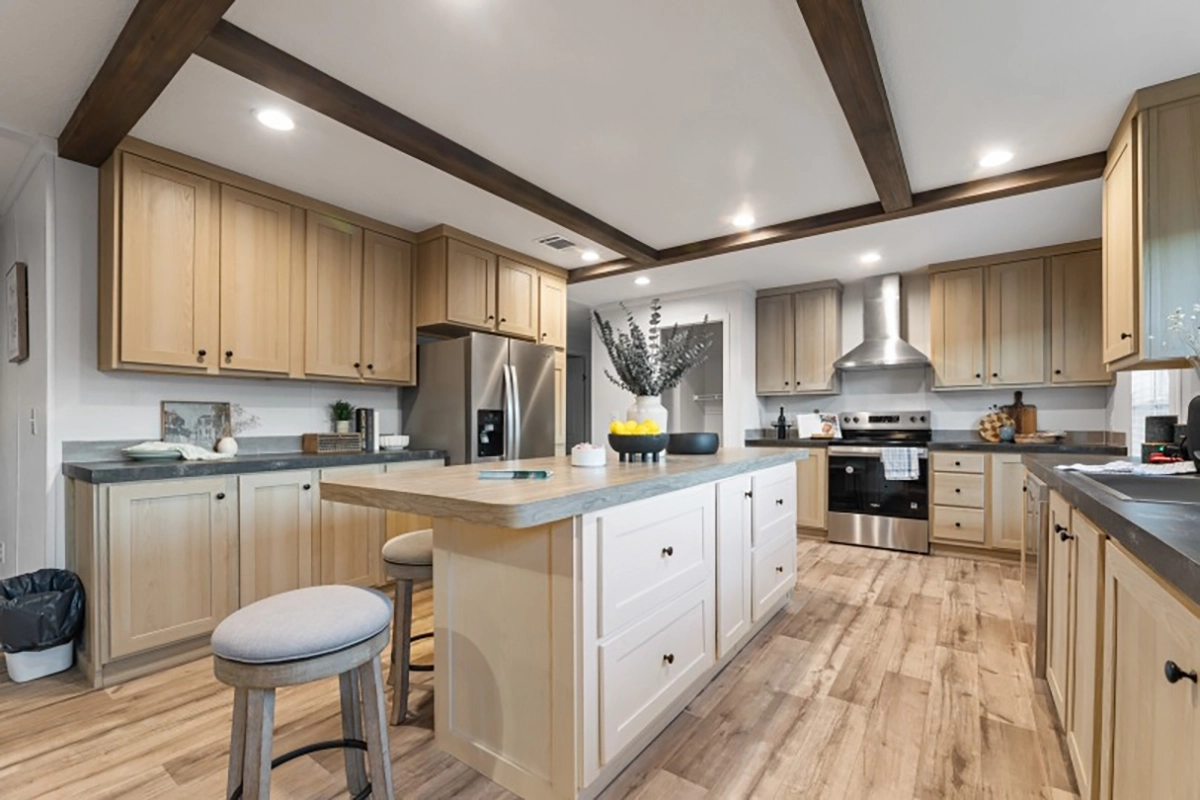 Spacious modern kitchen with light wood cabinets, stainless steel appliances, a large island with seating, and wood beam ceiling accents.