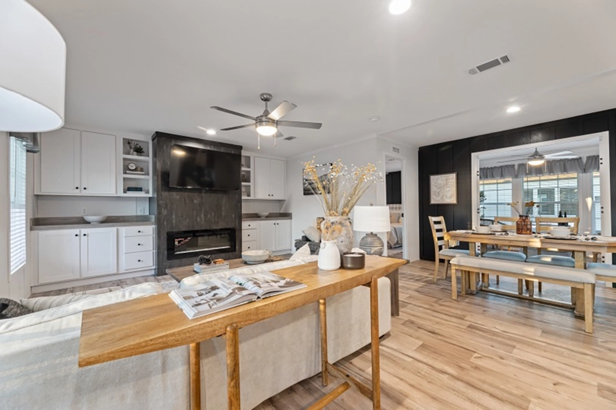 Modern open-concept living and dining area with light wood flooring, neutral furniture, built-in cabinets, a wall-mounted TV, and decorative accents on tables.