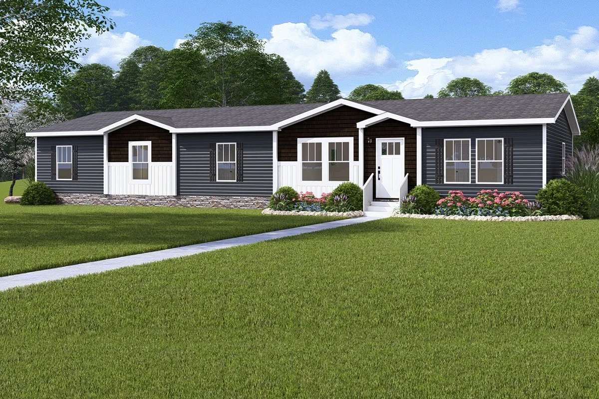 2cdc12de-b943-4559-b36e-0339dfeb790c A single-story, modern manufactured home with dark gray siding, white trim, a small front garden, and a wide green lawn under a partly cloudy sky.