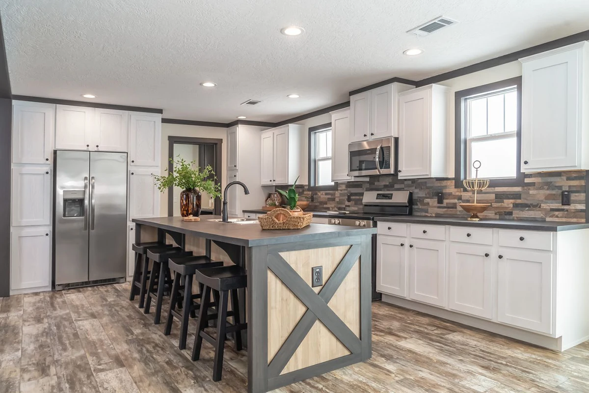 Modern kitchen with white cabinets, stainless steel appliances, a large island with seating, wood-style flooring, and a stone tile backsplash.