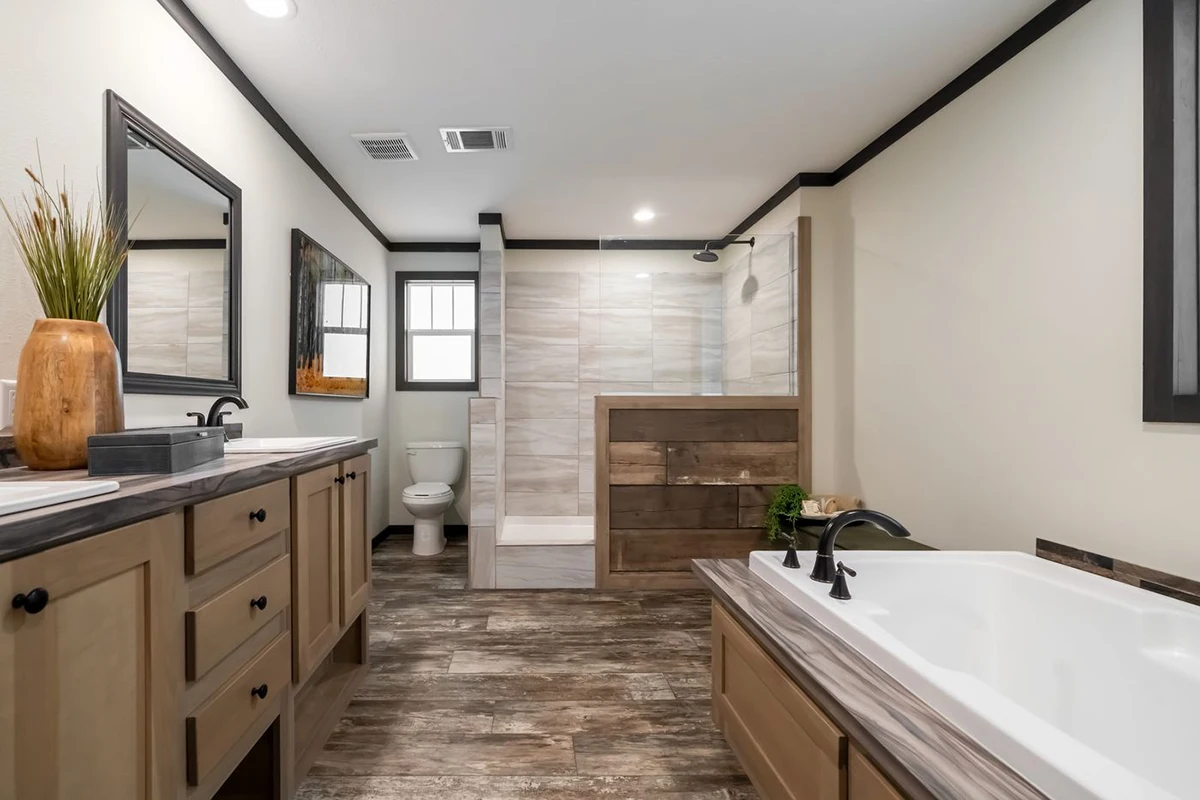 5f2c97ae-8c7d-44a6-8254-b48759e2ffe2 Spacious bathroom featuring a double vanity, bathtub, walk-in shower with glass partition, and toilet, all with wood accents and neutral tones.