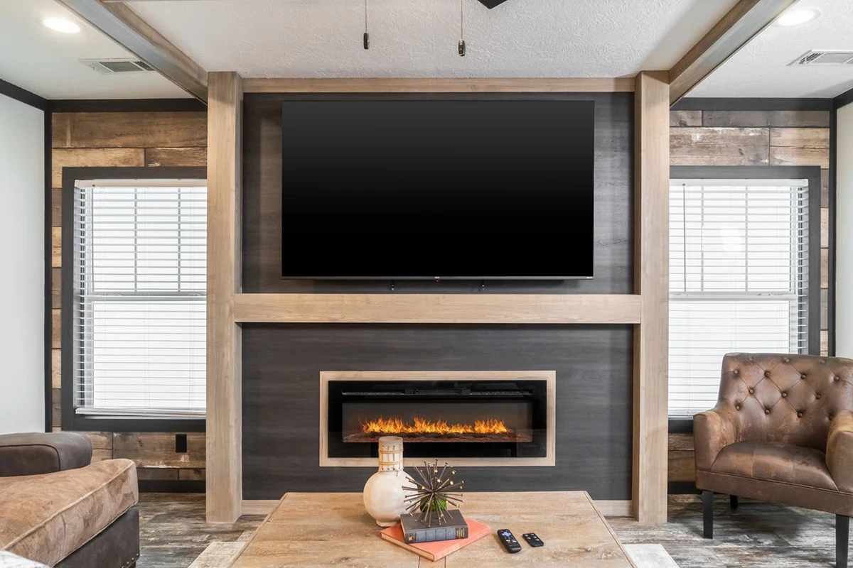 6d15aec0-3a0e-4073-a0a3-f87e28747530 Modern living room with a wall-mounted TV above an electric fireplace, flanked by two windows, and a coffee table with decor in front.