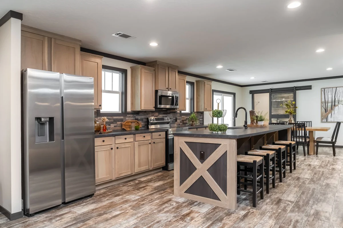 c7e51a77-5420-4b3f-b035-d92b66eb3199 Modern kitchen with stainless steel appliances, light wood cabinets, a large island with barstools, and a dining area in the background.