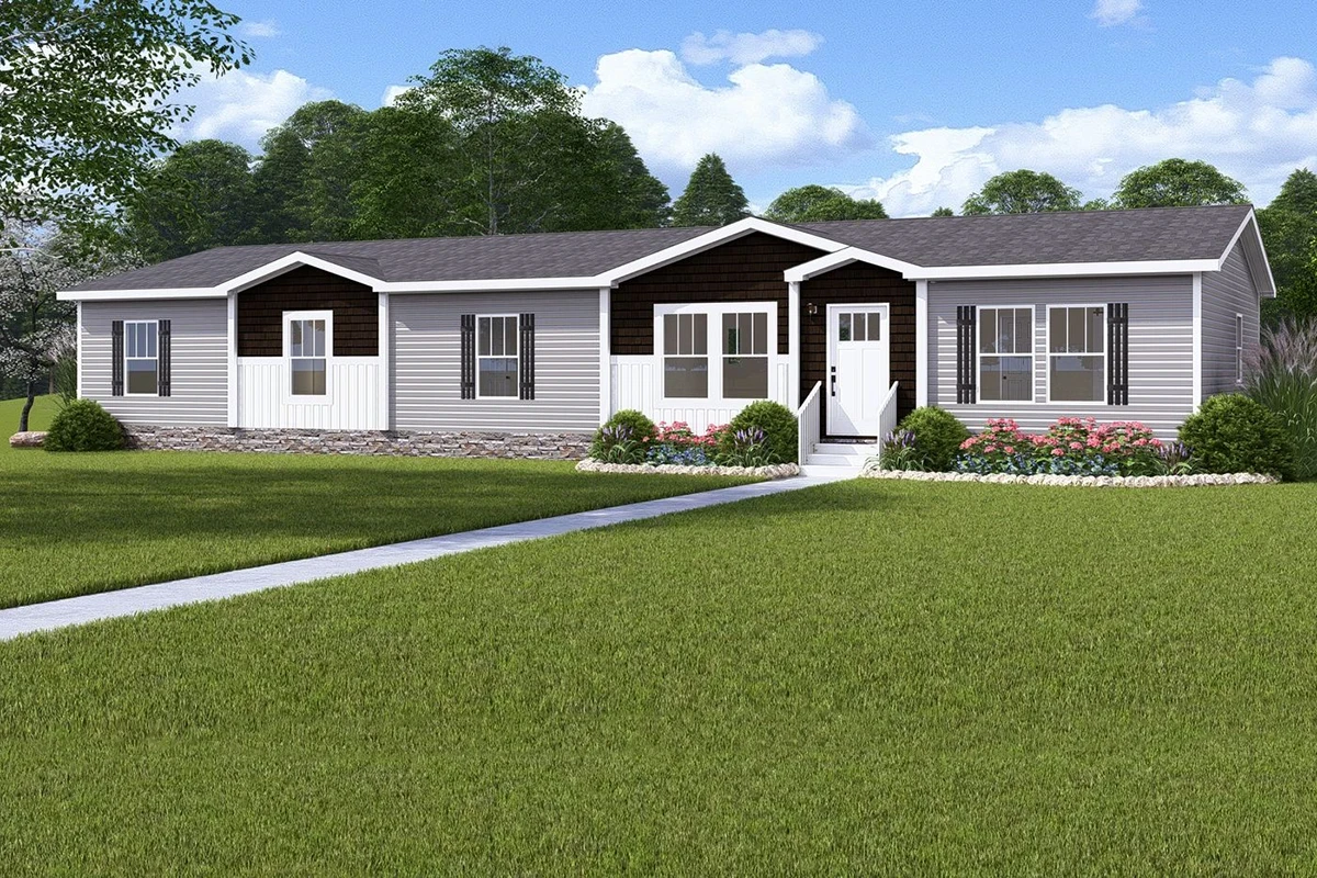 cf26cc43-ce07-49e7-959b-6fb68ed0c974 Single-story manufactured home with gray siding, dark shutters, and a front porch, surrounded by landscaped shrubs and a large green lawn. Trees and blue sky in the background.
