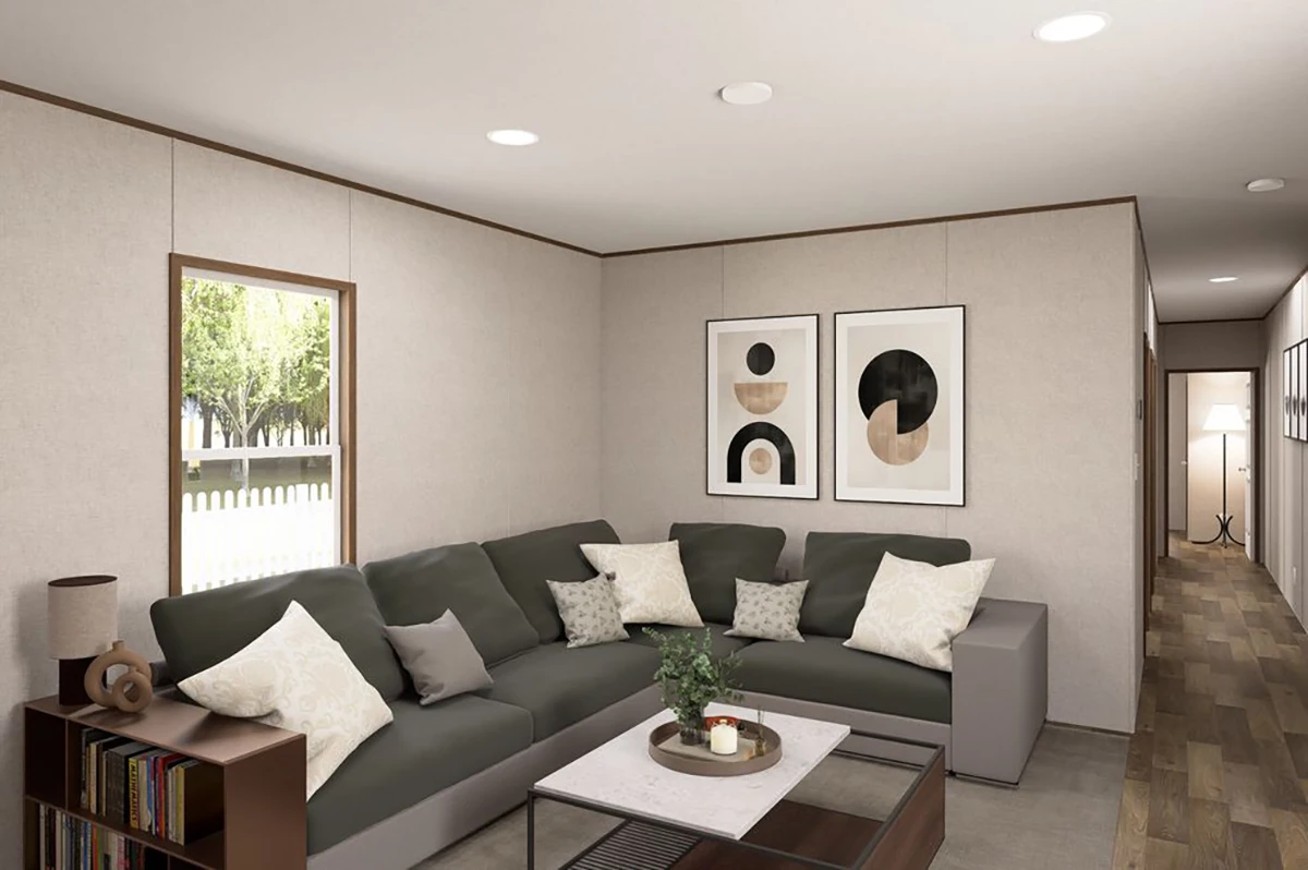 012831ef-7dfa-4e16-ae46-fe2876ede785 A modern living room with a gray sectional sofa, decorative pillows, a coffee table, abstract art on the wall, and a window showing greenery outside.