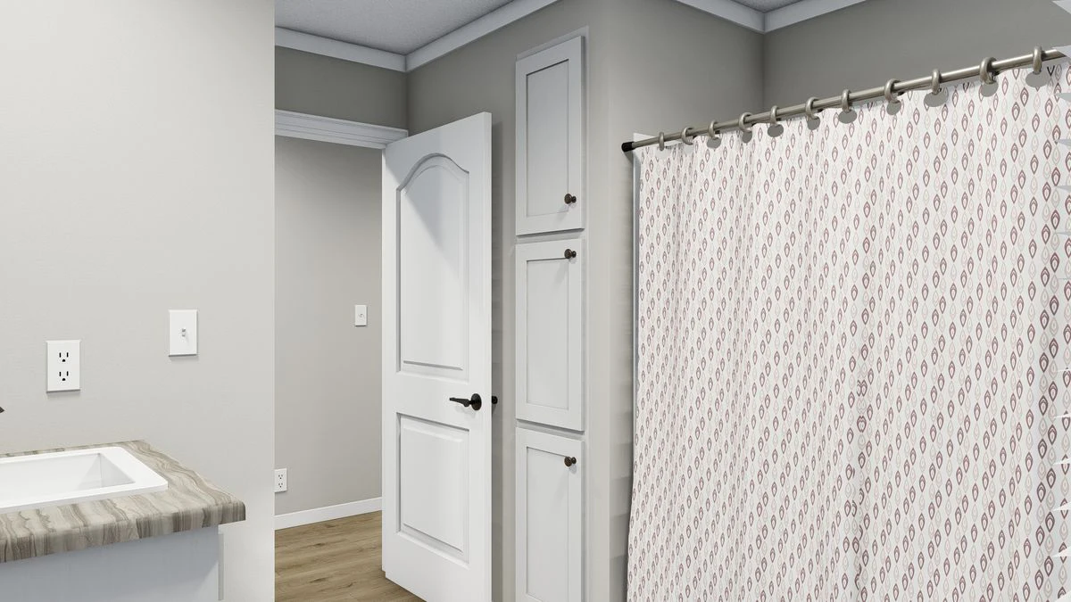 A bathroom with a patterned shower curtain, built-in storage cabinets, an open door, light gray walls, and a wood-look floor.