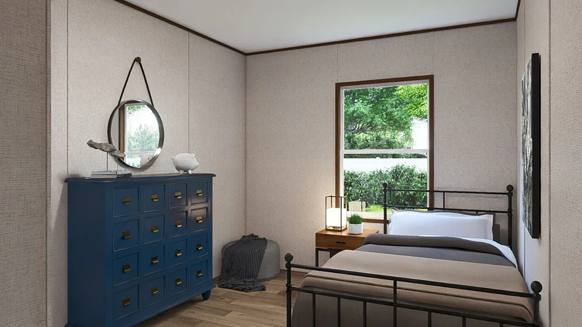06c8f318-3a88-4688-9849-ae3fb85e66e3 A small bedroom with a single metal bed, a blue dresser with a round mirror, a wooden nightstand, and a window showing greenery outside.