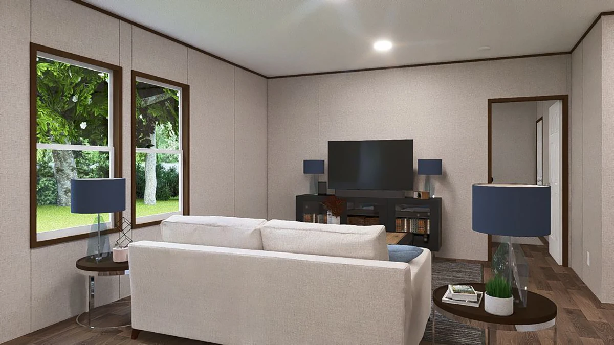 A modern living room with a white sofa facing a TV on a black stand, two windows showing greenery, and matching blue lamps on side tables.