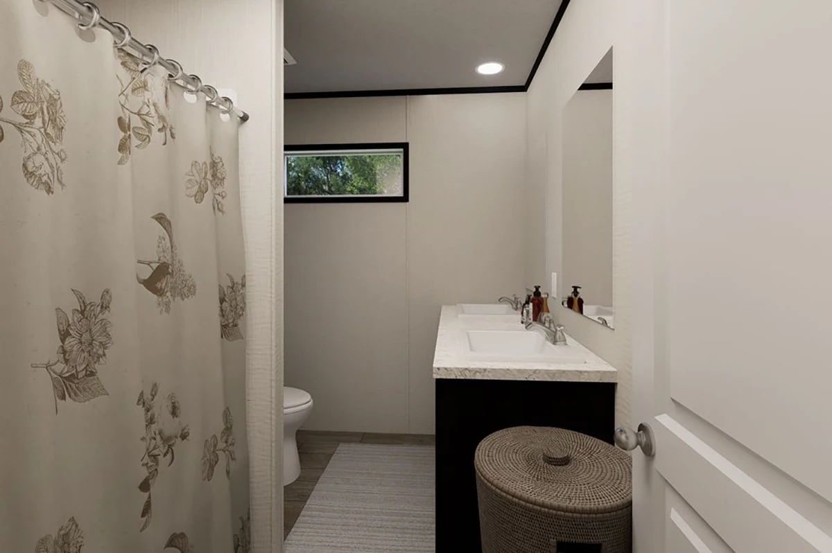 142bb1b9-280b-403f-9665-e77bf1da1423 A bathroom with a floral shower curtain, toilet, sink with toiletries, wall mirror, small window, and a woven laundry basket on a rug.
