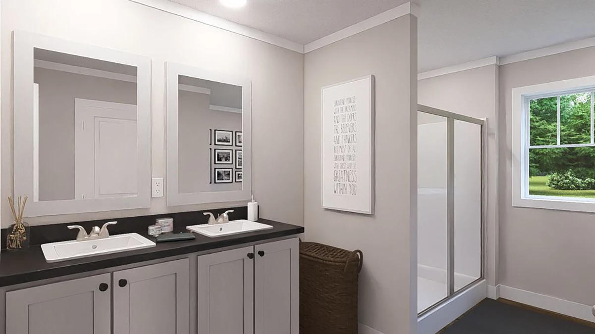 Modern bathroom with double sinks, black countertop, two mirrors, a wicker laundry basket, walk-in shower, and a window overlooking greenery. Neutral-colored walls and cabinets.