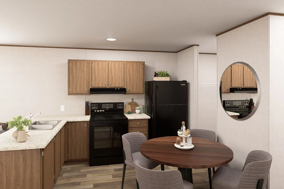 A compact kitchen with wood cabinets, black appliances, a round dining table with four chairs, a potted plant, and a round wall mirror.