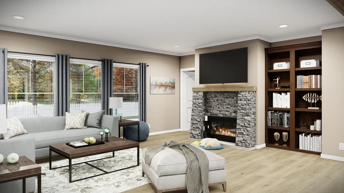 17e44b22-9aff-4d21-9285-fd9a0dcc6e63 Modern living room with a gray sectional sofa, stone fireplace, wall-mounted TV, built-in bookshelves, large windows with gray curtains, and wooden floors.