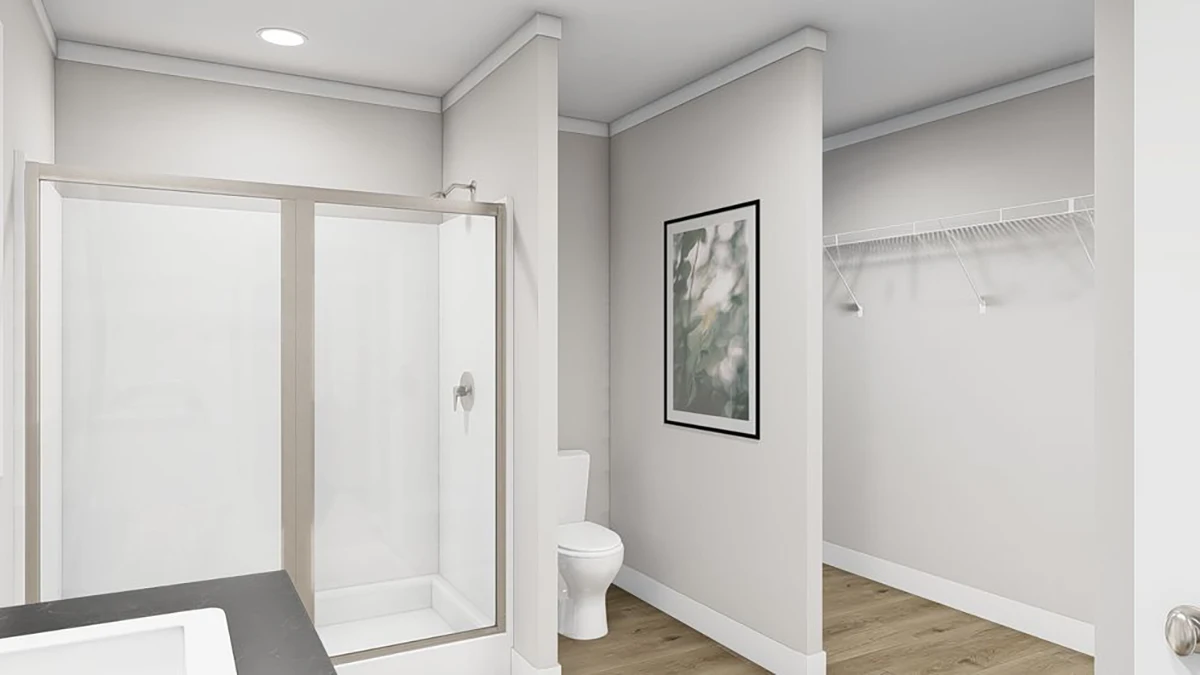 189bee68-b173-4108-93c9-4663906ef955 Modern bathroom with a glass shower, toilet, wall art, and an adjacent closet with wire shelving, featuring light-colored walls and wood flooring.