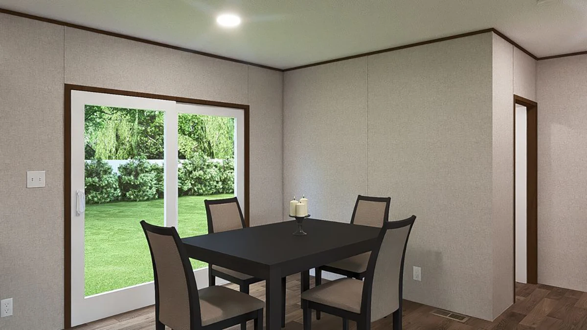 A dining area with a black table, four chairs, a candle centerpiece, wood floors, and sliding glass doors overlooking a green backyard.