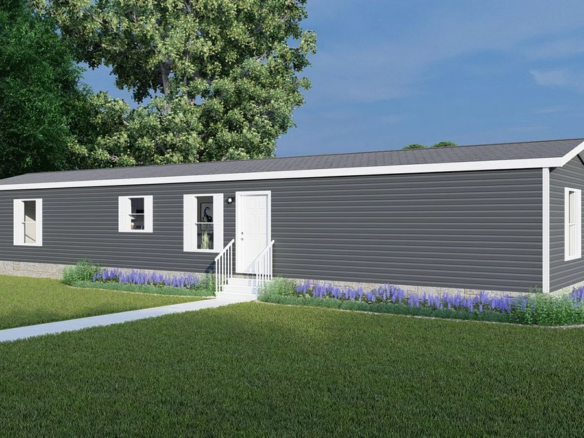 A modern single-wide mobile home with gray siding, white trim, and a small front stoop, surrounded by grass, purple flowers, and a white fence.