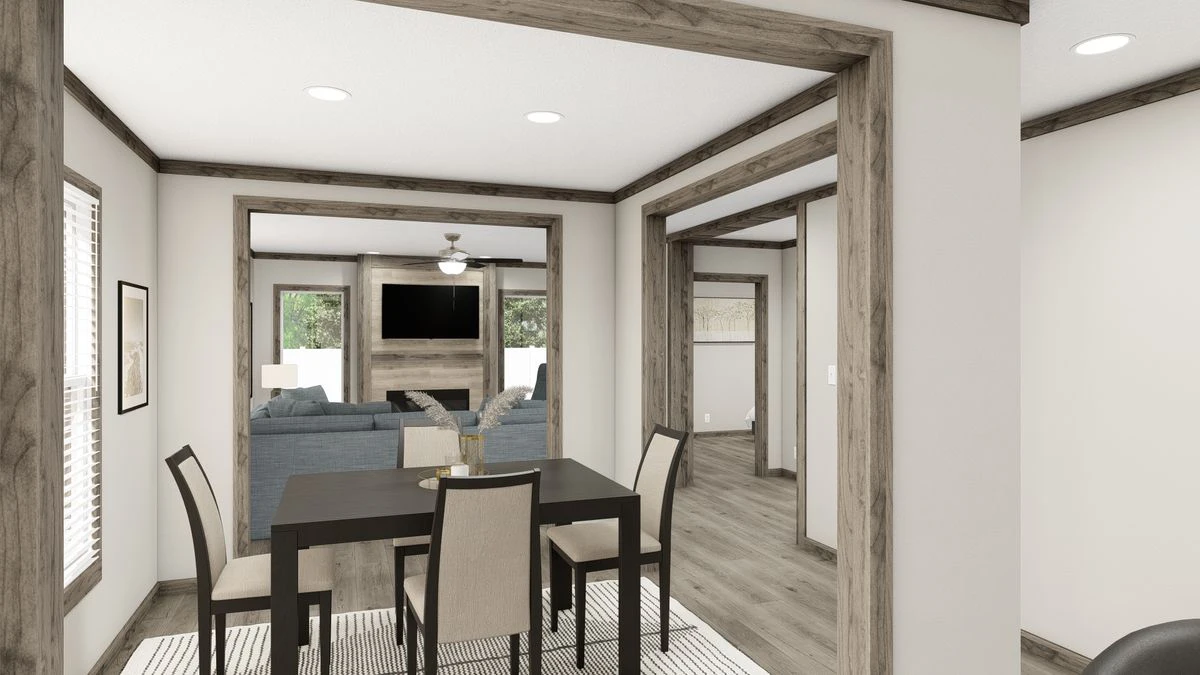 Open-plan dining and living area with neutral tones, wood trim accents, a dining table with four chairs, and a sitting area with a TV and sofas in the background.