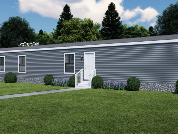 A gray single-wide manufactured home with white trim, front door with steps, and small shrubs in front, set on a green lawn with trees in the background.