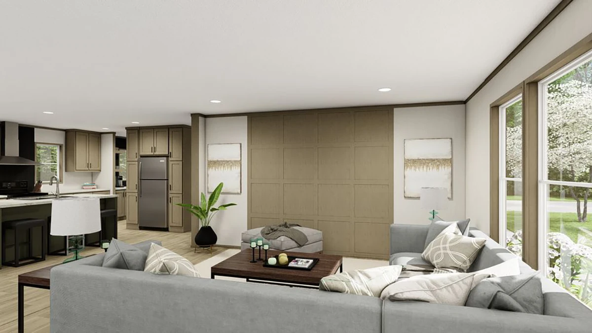 1f5f1096-021d-4d93-85dc-675a3950a3e8 Modern living room with gray sectional sofa, ottoman, coffee table, large windows, and open view to kitchen with bar seating. Neutral decor and indoor plant enhance the space.