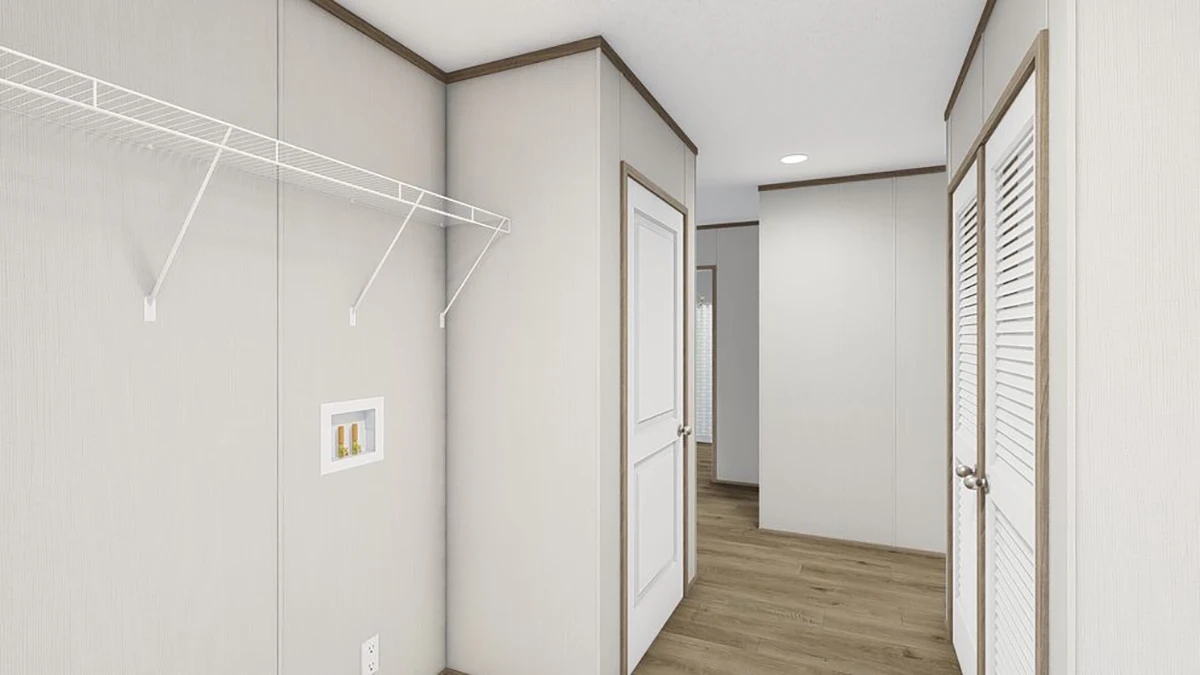 A hallway with light-colored walls, wood flooring, a white door, closet doors, and a wire shelf on the left wall.