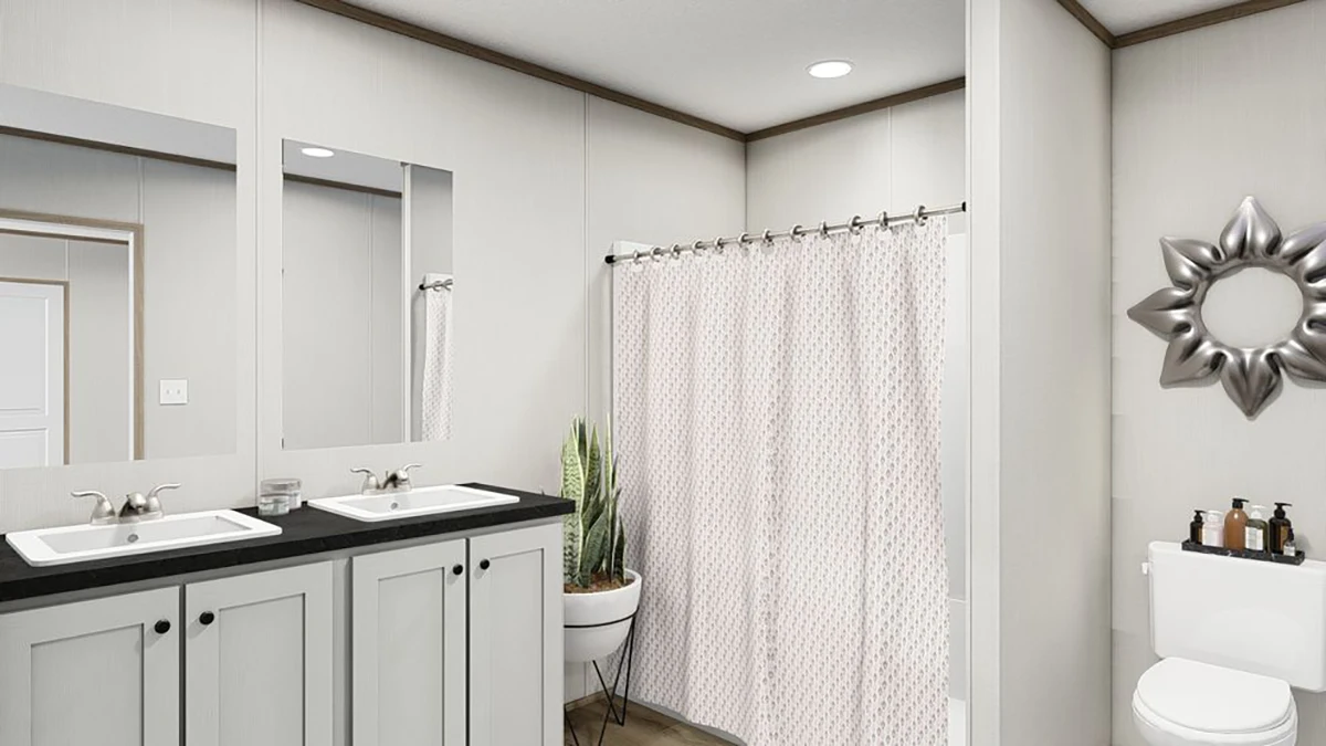 Modern bathroom with double sinks, a potted plant, a shower with a patterned curtain, a toilet, and a decorative mirror on the wall.