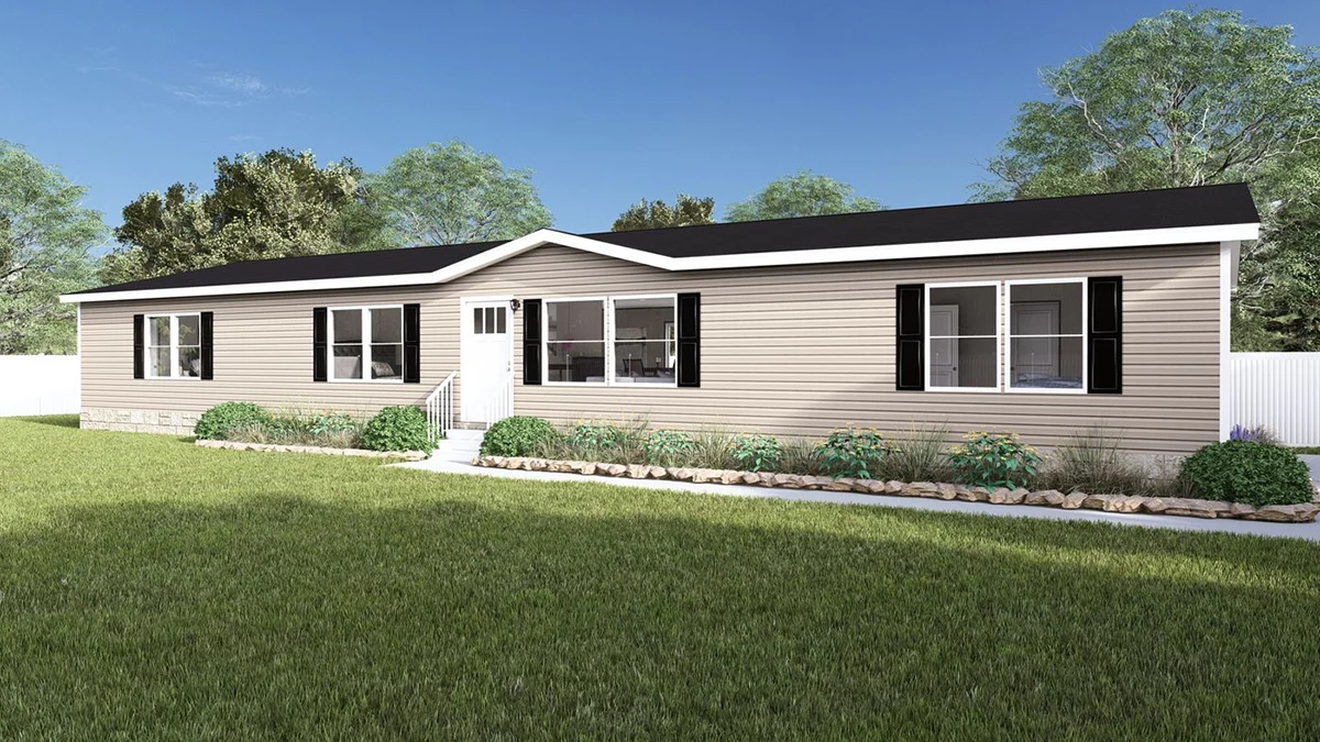 23718dfb-146b-46f5-bed8-29b756b1da7b A beige single-story manufactured home with black shutters, white trim, and a small front porch, set on a grassy lawn with shrubs and a white fence in the background.