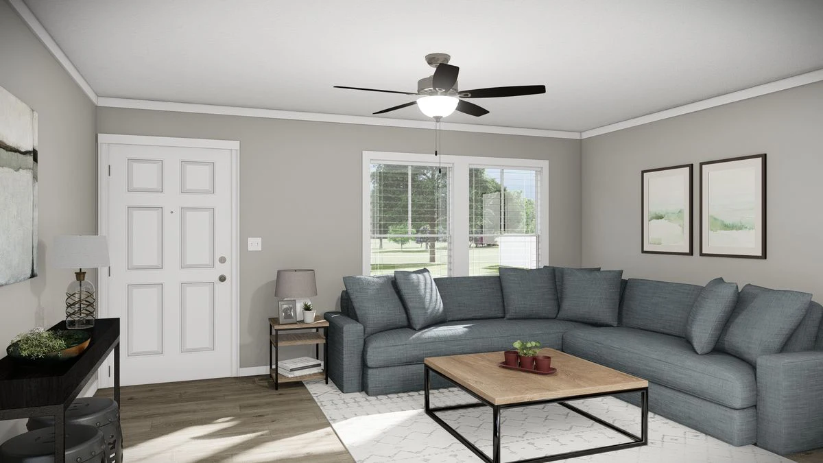27d34ef8-e7eb-42d4-bd66-48259d9ccf92 A living room with a gray sectional sofa, wooden coffee table, and side table. Large window lets in natural light. Ceiling fan with light is on, and framed art decorates the walls.