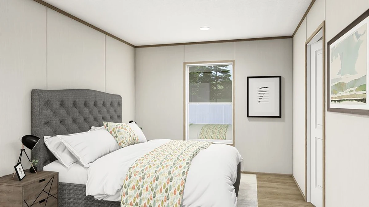 2f716358-2d54-46f4-ac56-68d73bc87caf A modern bedroom with a gray upholstered bed, white bedding, two framed pictures on the walls, a bedside table with a lamp, and a window letting in natural light.