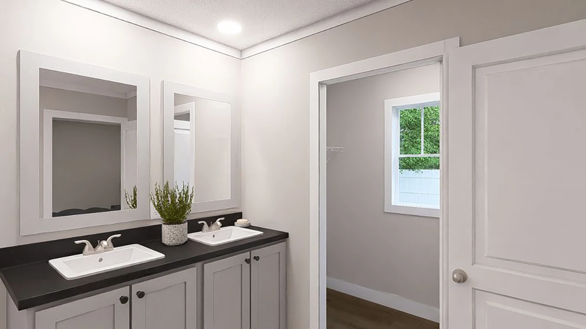 A modern bathroom with double sinks, white cabinets, two mirrors, a potted plant, and an open door leading to a room with a window.