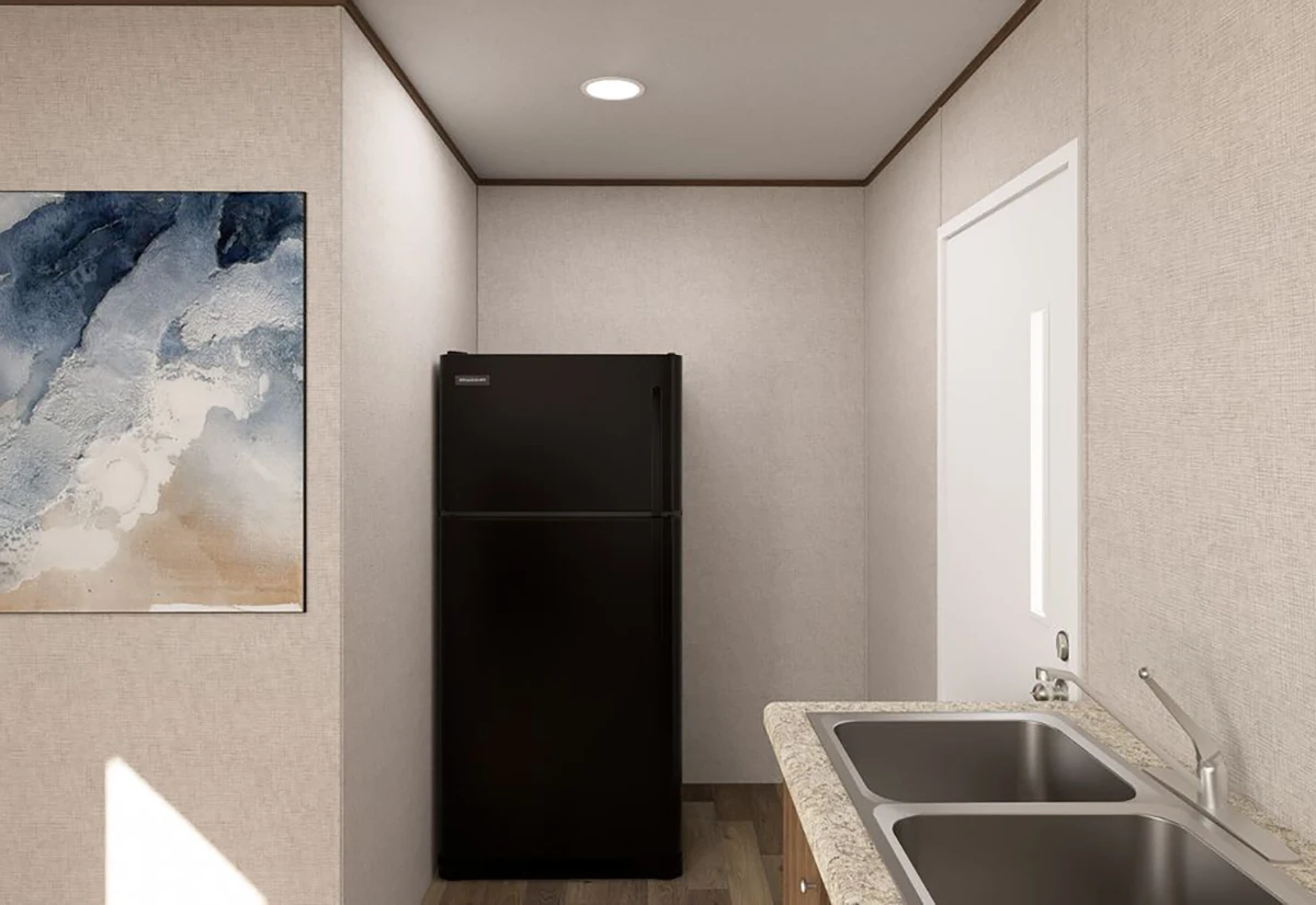 A small kitchen features a black refrigerator, a double sink with a granite countertop, a white door, and an abstract painting on the wall.