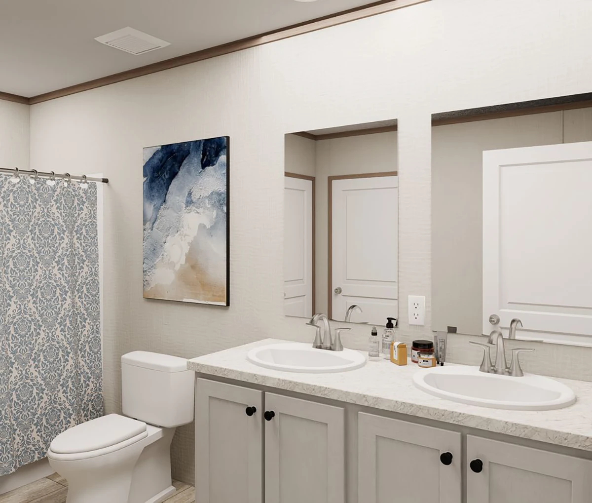 Modern bathroom with double sinks, a toilet, patterned shower curtain, large mirror, and abstract wall art above the toilet.