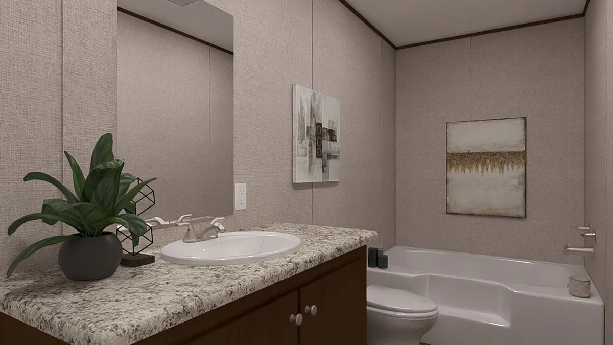 Bathroom with a granite countertop, sink, potted plant, bathtub, and wall art on beige walls. A mirror reflects the space above the sink.