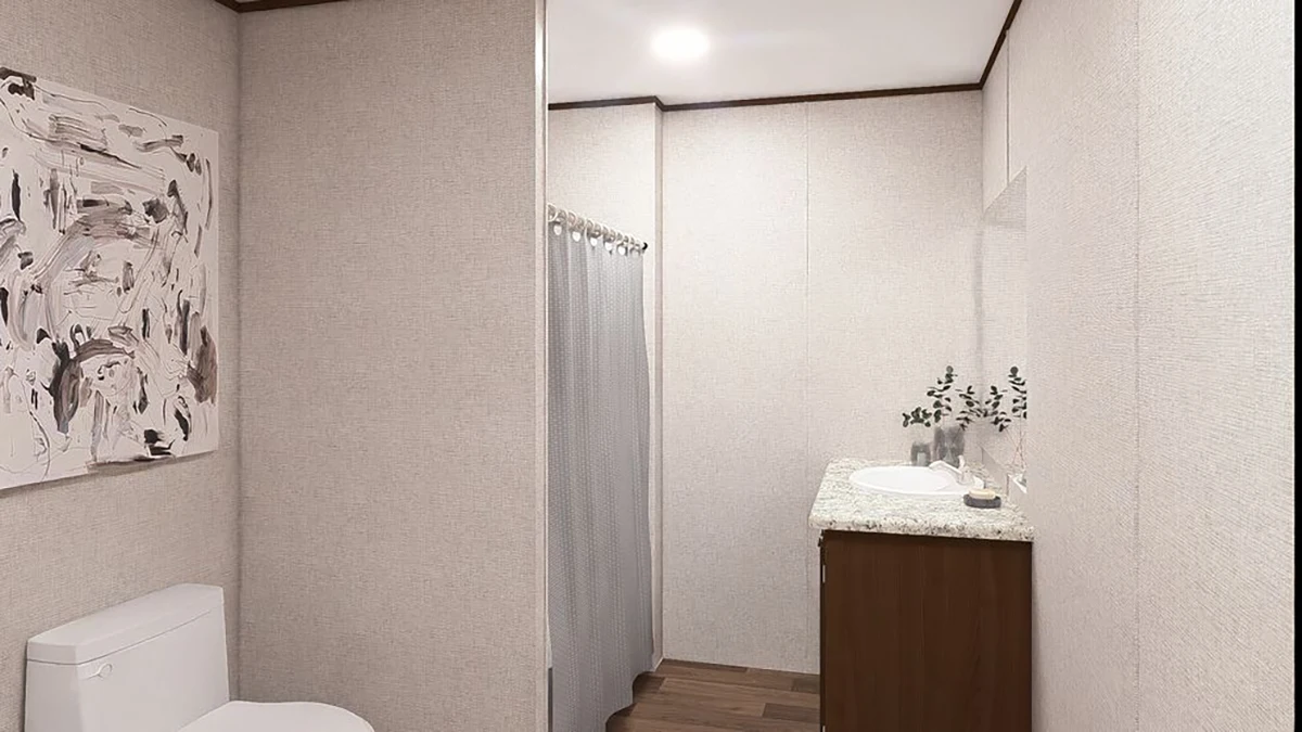 A bathroom with a toilet, a shower with a curtain, a vanity with a sink, and a countertop with decor; abstract art hangs on the wall.