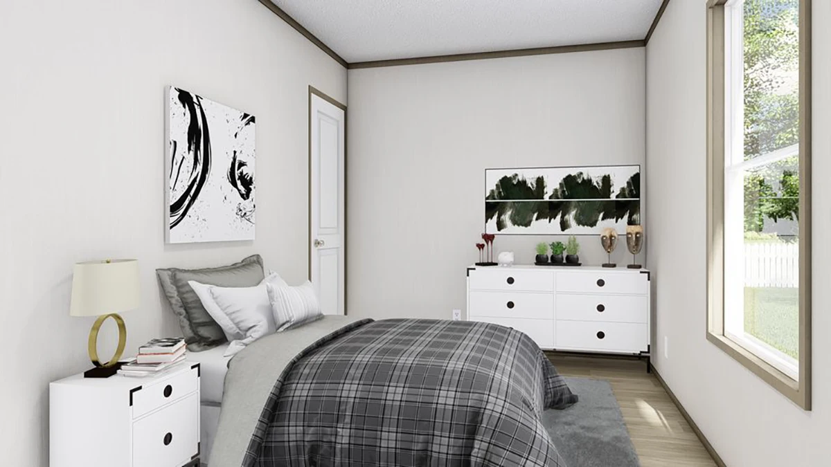 A modern bedroom with a plaid bedspread, white dresser, bedside table with lamp, abstract art on the walls, and a large window letting in natural light.